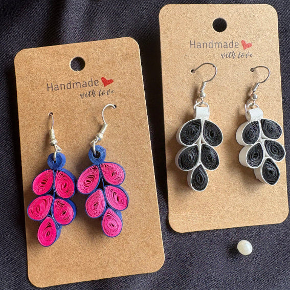 Two pairs of quilled earrings on 'Handmade with Love' cards against a dark background.