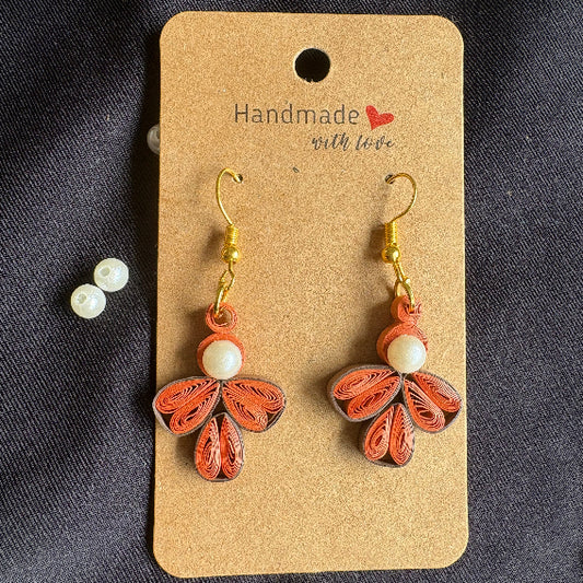 Butterfly-shaped earrings on a 'Handmade' card with pearls on a dark background