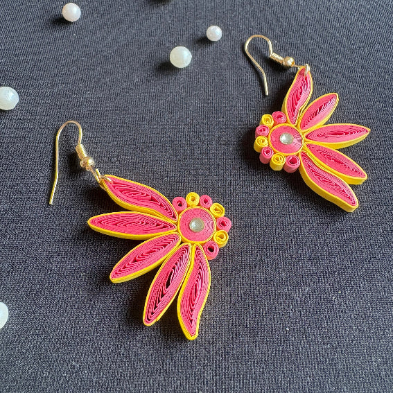 Pair of pink and yellow quilled earrings on a dark background