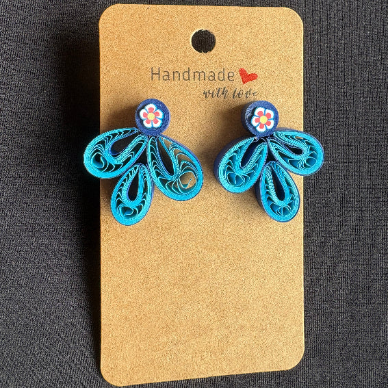Blue butterfly-shaped earrings on a brown card with 'Handmade with Love' text against a dark background