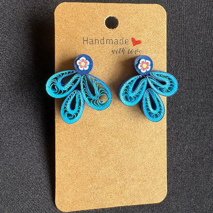 Blue butterfly-shaped earrings on a brown card with 'Handmade with Love' text against a dark background