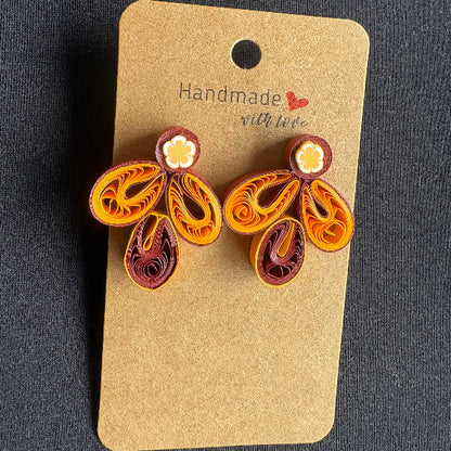 Pair of quilled earrings on a 'Handmade with Love' card against a dark background