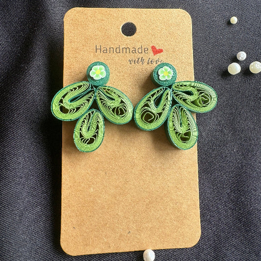Green leaf-shaped earrings on a 'Handmade with Love' card against a dark fabric background.