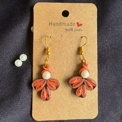 Butterfly-shaped earrings on a 'Handmade' card with pearls on a dark background