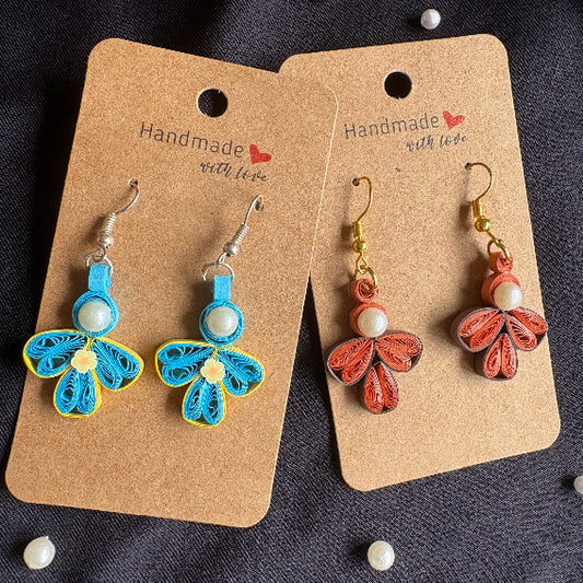 Butterfly-shaped earrings on brown cards with 'Handmade with Love' text, on a dark fabric background.
