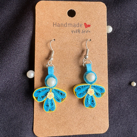 Blue and yellow butterfly-shaped earrings on a 'Handmade with Love' card against a dark fabric background.