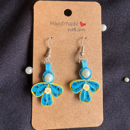Blue and yellow butterfly-shaped earrings on a 'Handmade with Love' card against a dark fabric background.