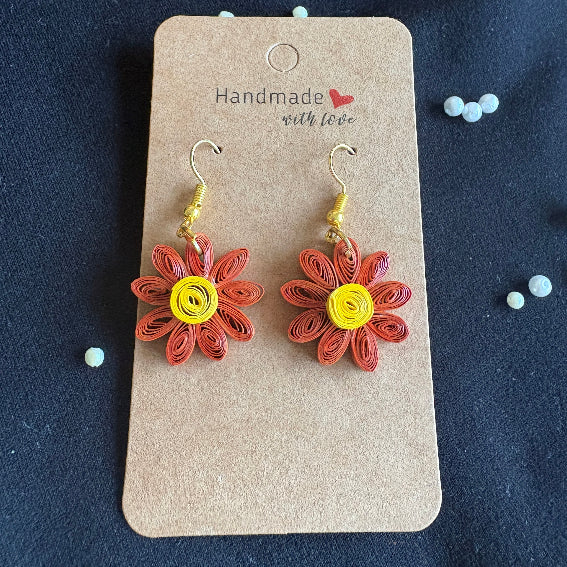 Flower-shaped earrings on a 'Handmade with Love' card against a dark background