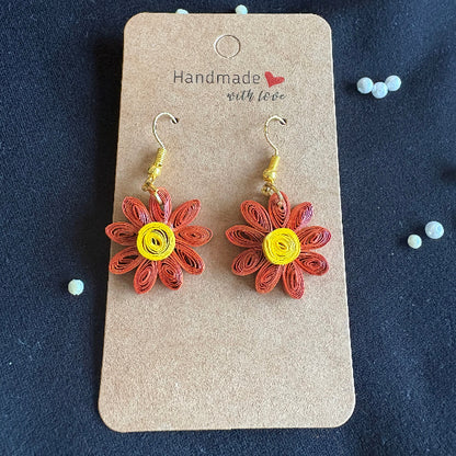 Flower-shaped earrings on a 'Handmade with Love' card against a dark background