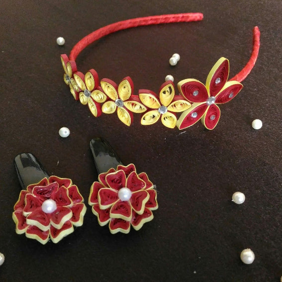 Floral headband and earrings with red and yellow flowers on a dark surface.