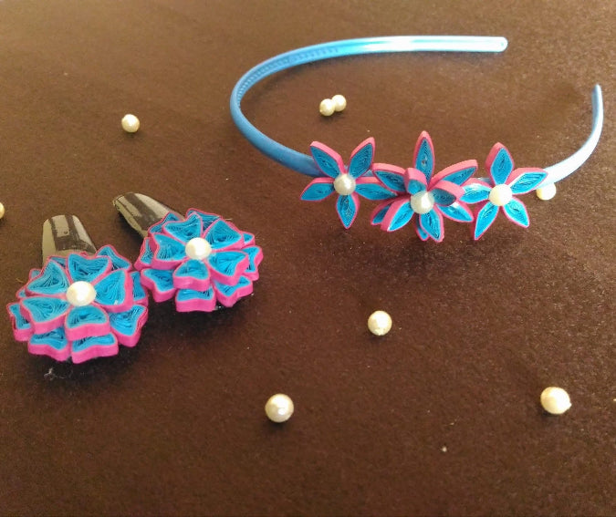 Floral headband and clips with pink and blue flowers on a brown surface.