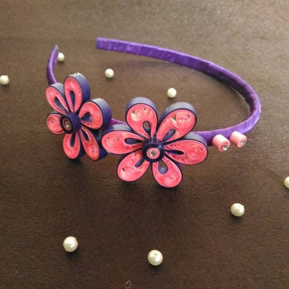 Purple headband with pink flowers on a brown surface